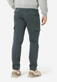 Graue Cargo-Hosen mit mehreren Taschen, schmalem Schnitt und glatter Textur. Tragen Sie dazu hellfarbige Sportschuhe.