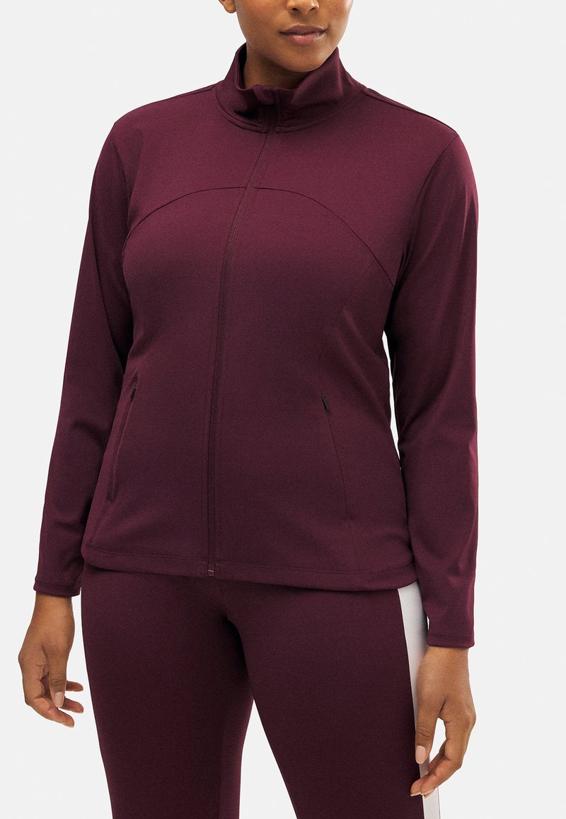 Chaqueta de cremallera burdeos con cuello alto y mangas largas; cuenta con dos bolsillos laterales y una textura suave y elástica.