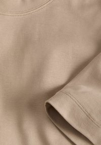 Beige katoenen t-shirt met een ronde hals, korte mouwen en een gladde textuur met subtiele stiksels langs de zoom.