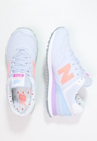 Baskets bleu clair avec des accents roses et un design perforé. Comprend un col rembourré, une semelle texturée et des semelles intérieures à motifs.