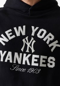 Sweatshirt preto com texto bordado branco "NEW YORK YANKEES" e "Desde 1903", apresentando um design de logotipo clássico e uma textura de tecido suave.