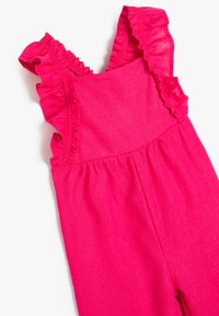 Fuchsia rosa byxdress med volangaxelremmar, tillverkat av mjukt tyg. Har en samlad midja och vida byxben för en avslappnad passform.