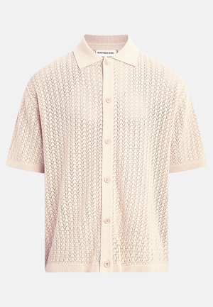 Polo en tricot rose clair à manches courtes avec boutons sur le devant, motif ajouré texturé, col et bords des manches et de l'ourlet côtelés.