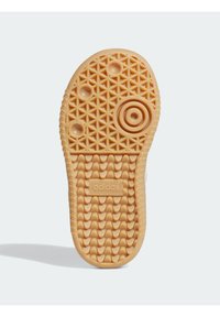 Gummisohle in Beige mit diamantförmigem Muster, runden Details und dem eingeprägten "adidas"-Logo in der Nähe der Ferse.