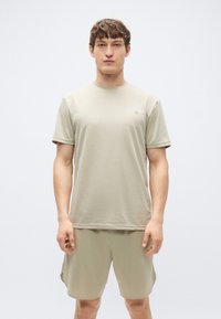 T-shirt de manga curta bege claro com decote redondo, combinada com calções texturizados ao mesmo tom. Ambas as peças apresentam um design minimalista e um corte ajustado.