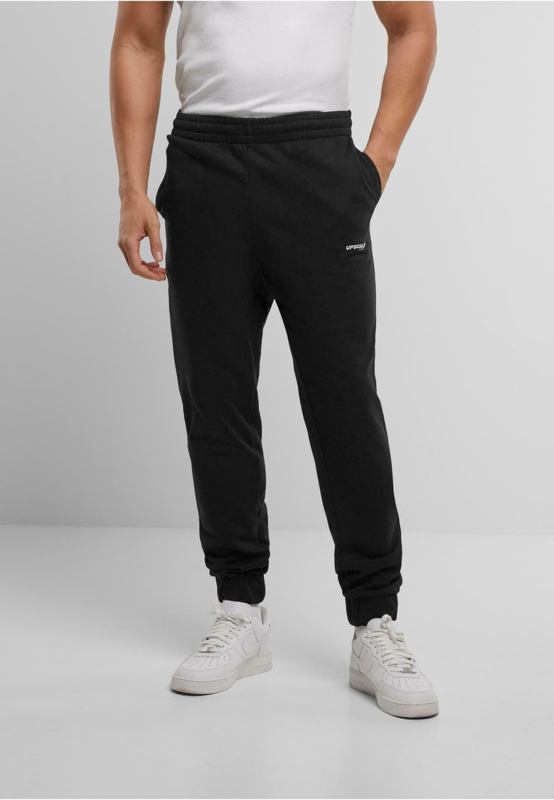 Zwarte sweatpants met een elastische tailleband, zijzakken en geribbelde manchetten. Heeft een klein wit logo op de linker dij.