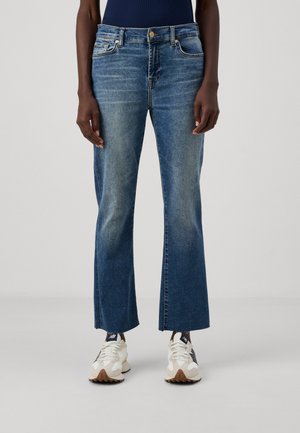 Blaue Jeans aus Denim mit hoch geschnittenem, weiten Schnitt, verblasster Textur und zwei Fronttaschen, kombiniert mit hellen Sneakern.