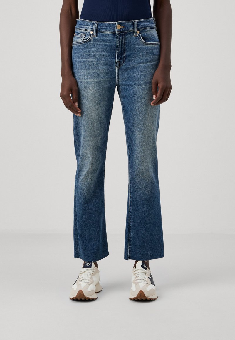 Blå denimjeans med hög midja, vid passform, urblekt textur och två framfickor, tillsammans med ljusa sneakers.