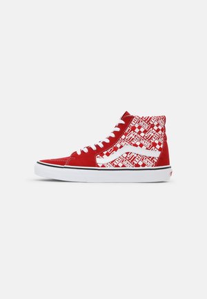 Baskets montantes rouges et blanches avec lacets blancs, bande latérale Vans et motif de texte graphique sur la tige.