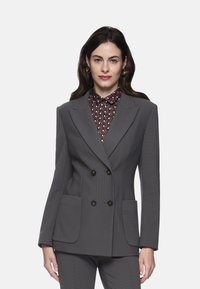 Gray double-breasted blazer with textured fabric, two front pockets, and black buttons, paired with a patterned collared shirt beneath.
