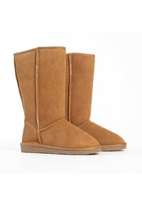 Botas de ante marrón hasta la rodilla con suela plana, que presentan costuras visibles y un diseño sencillo, textura suave y sin adornos.