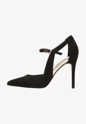 Musta mokkanahkainen korkokenkä, jossa on terävä kärkiosa ja nilkkaremmi, jossa on kullanvärinen solki. Sileä pinta ja ohut piikkikorko tarjoavat vakautta.