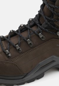 Donkerbruine wandelschoen met een gestructureerde leren bovenkant, versterkte oogjes, nylon veters en een stevige zwarte rubberen zool. Zichtbare stikseldetails.