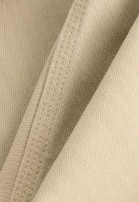 Beige fabric with a textured weave, showing multiple folds and visible stitching details. Material appears durable and heavy-weight.