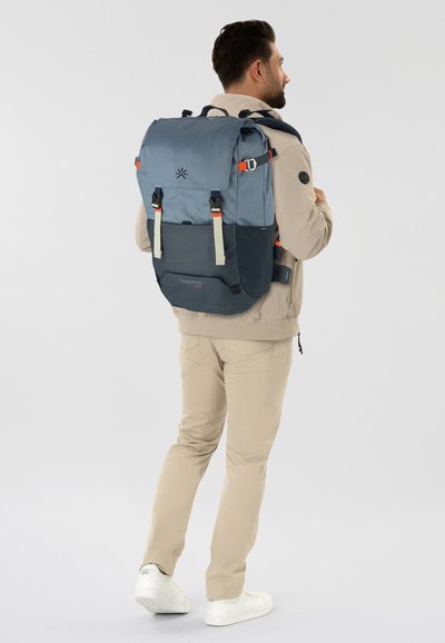 Mochila en azul marino y azul claro, hecha de un tejido duradero. Presenta correas ajustables, bolsillos laterales y un cierre plegable con acentos en metal.