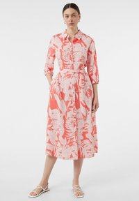 Koronkowa sukienka z białym kwiatowym wzorem, z guzikiem z przodu, rękawami o długości trzech czwartej, talią podkreśloną i długością midi. Noszona z białymi sandałami.