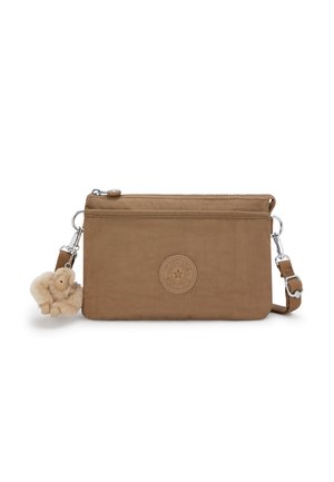Brown fabric crossbody bag with a logo patch, zipper closure, detachable strap, and a furry monkey charm attached. Smooth texture.