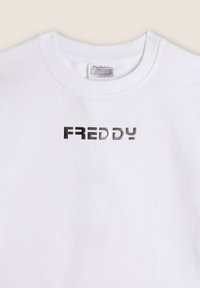 T-shirt bianca in cotone con scollo rotondo. Presenta un logo riflettente argento "FREDDY" in un carattere sans-serif moderno sul davanti.