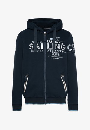 Marine blauwe rits-hoodie gemaakt van zachte stof. Voorzien van witte tekstgrafieken, voorzakken met ritsen en een geribde zoom met blauwe accenten.
