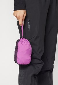 Borsa leggera e ripiegabile rosa e nera con chiusura a coulisse, tenuta da una mano, il tessuto ha una texture liscia e un motivo sottile.