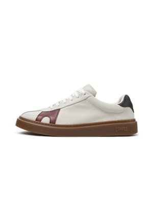 Zapatilla blanca de piel de perfil bajo con suela de goma marrón, detalle lateral burdeos, parche negro en el talón y cordones blancos, vista desde un lateral.