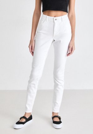 White high-waisted jeans with a snug fit, featuring front pockets, a button closure, and a slightly textured fabric. Paired with black shoes.
