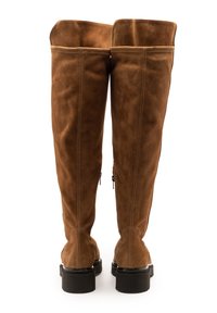 Braune Overknee-Stiefel aus Wildleder mit glattem Finish, flachen schwarzen Gummisohlen, Reißverschlüssen an den Seiten und gesteppten Details.