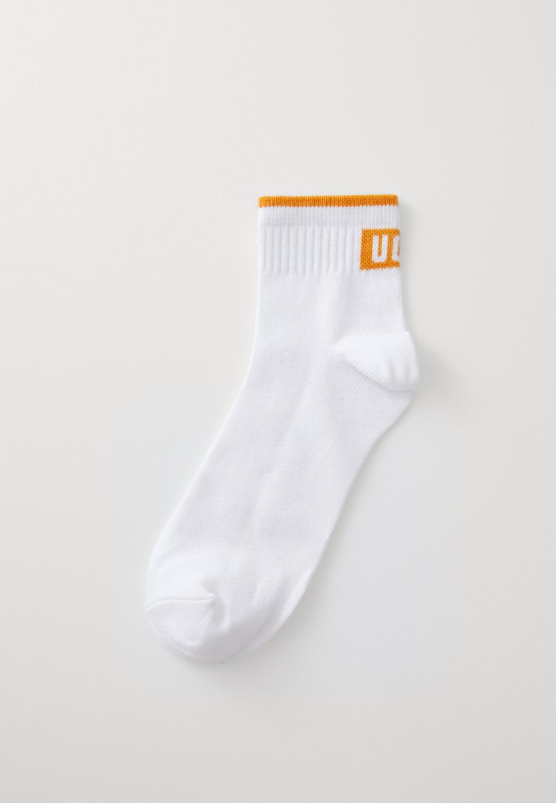 Bijela pamučna čarapa s narančastim rebrastim rubom na kojem se nalaze slova "U" i "C" u bloku. Glatka tekstura, dizajn do gležnja.