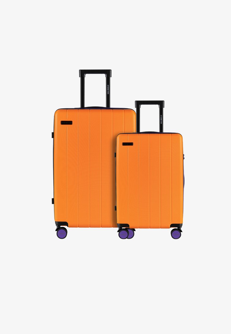 Dwie twarde walizki w jaskrawym pomarańczowym kolorze, z teksturowanymi powierzchniami, poziomymi rowkami, czarnymi uchwytami i fioletowymi kołami.