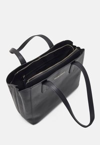 Borsa tote in pelle nera Valentino con due manici sottili, un compartimento centrale con zip e un logo dorato visibile sul davanti.