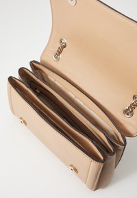 Béžová syntetická kabelka se třemi přihrádky, s texturovaným povrchem, zlatými doplňky a uzávěrem na klapku.