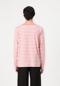 Dryžuota ilgomis rankovėmis marškinėliai šviesiai rožinės ir baltos spalvos, su apvaliu iškirpimu ir laisvu siluetu, turi rūbų kraštų mezgimo detales. Lygus medvilnės audinys.