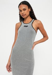 Robe sans manches grise avec une silhouette ajustée, fabriquée à partir d'un matériau texturé, dotée d'une bordure noire et d'un logo au niveau de la poitrine.
