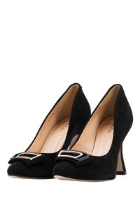 Un paio di scarpe nere in suede con tacco alto, dotate di una fibbia decorativa quadrata oro e nera su ciascun dito.