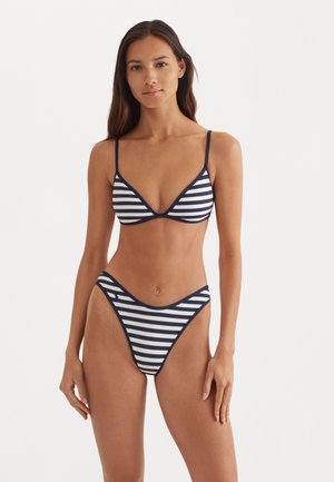Raitotā bikiniju komplekts tumši zils un balts, ar trīsstūrveida krūšturi ar plānām siksniņām un atbilstošām zemu vidukļa bikini apakšdaļām ar V-veida griezumu.