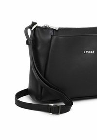 Bolso bandolera de cuero negro con un acabado texturizado, cierre de cremallera y correa ajustable. Presenta un detalle del logo plateado en la parte frontal.