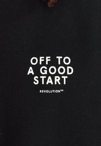 Zwarte sweatshirt met witte tekst: "OFF TO A GOOD START" en "REVOLUTION™." Gemaakt van zachte, gestructureerde stof met een ontspannen pasvorm.
