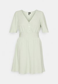 Světle zelené šaty s krátkým rukávem z texturované látky, které mají výstřih do V, přední zapínání na knoflíky a elastický pas, vytvářející rozšířenou siluetu.