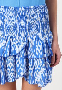 Blauwe en witte gestreepte rok met een elastische tailleband, gerimpelde lagen en een zachte stofstructuur. Heeft een speels, vloeiend ontwerp.
