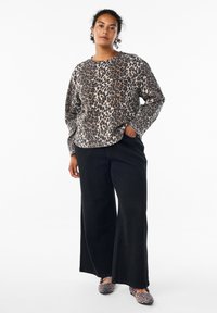 Leopard-print sweatshirt in soft fabric with a rounded neckline. Paired with wide-leg black pants and leopard-print shoes.