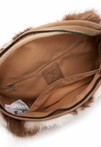 Bruine nepbont tasinterieur met een gladde beige voering, een ritsvak en een klein leren label. Ritsopening aan de bovenkant.