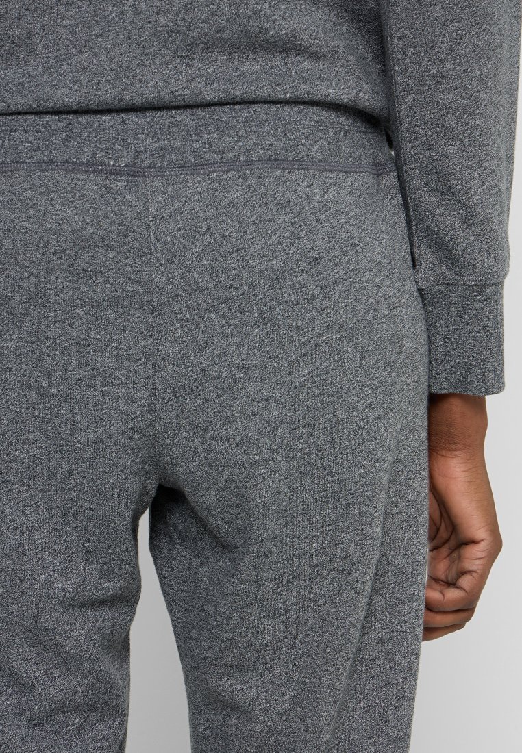 Szare dresy wykonane z miękkiej mieszanki bawełny, z gładką talią i dopasowanym krojem z minimalną liczbą szwów oraz brakiem widocznych zdobień.