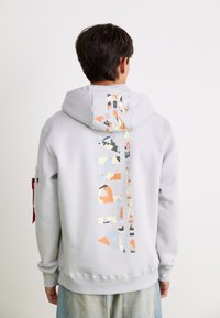 Felpa grigia con una grande grafica multicolore sul retro. Presenta un cappuccio, polsini a coste e un'etichetta con logo sulla manica. Materiale in misto cotone.