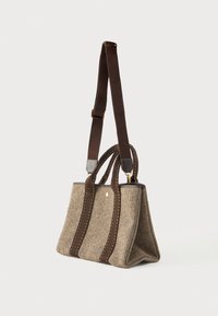 Ορθογώνια μπεζ τσάντα ώμου από ύφασμα με σκούρους καφέ χειρολαβές και ρυθμιζόμενο λουρί, με χρυσές λεπτομέρειες και αντίθετη ραφή.