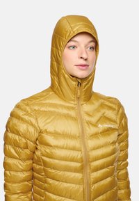 Gelbe isolierte Jacke mit Kapuze, versehen mit einem gesteppten Design, Reißverschluss und einem Logo auf der Brust. Glatte, glänzende Textur.