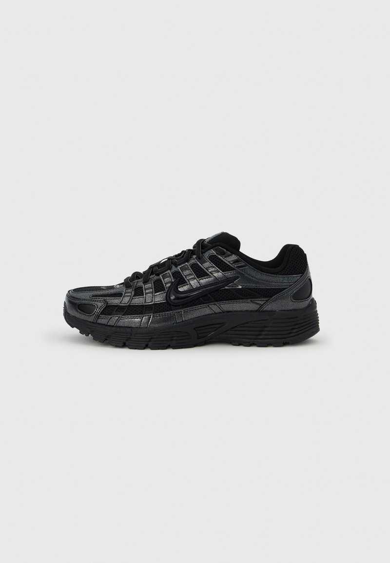 Baskets athlétiques noires et gris foncé avec un design synthétique en couches, une semelle épaisse et un logo Nike Swoosh noir sur un fond clair uni.