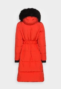 Červená péřová bunda s černou umělou kožešinou na kapuci, páskem v pase, dlouhými rukávy a prošívanou texturou. Zadní pohled ukazuje celou délku a designové detaily.