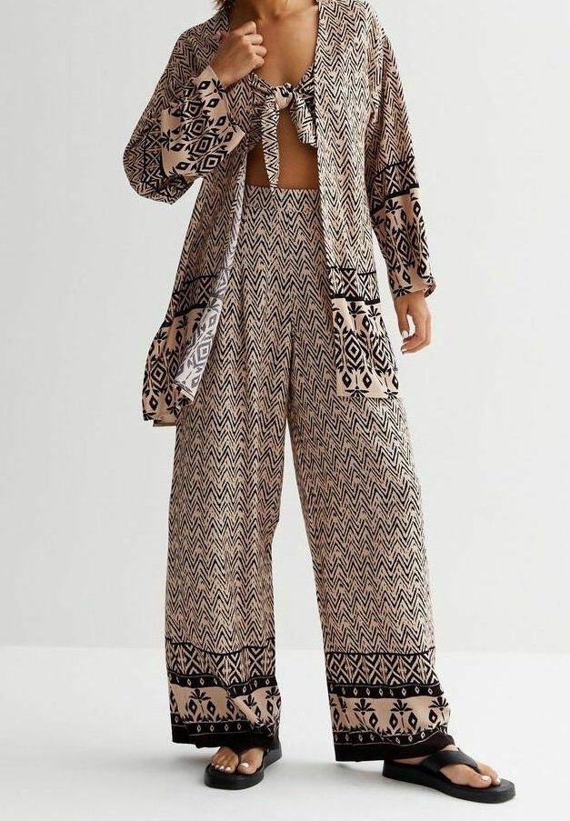 Luźny, wzorzysty zestaw składający się z dwóch części, z beżowym tłem i czarnymi wzorami w zygzaki oraz kwiatami. Zestaw zawiera top z węzłem oraz szerokie spodnie.