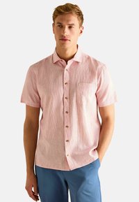 Lühem varrukaga helesinine nööbiga särk, millel on peen tekstuur, rinnatasku ning pruunid nööbid.