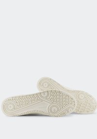 Sneakers bianchi con suola in gomma testurizzata, caratterizzati da un motivo ondulato e accenti circolari. Materiale superiore liscio e design minimalista.